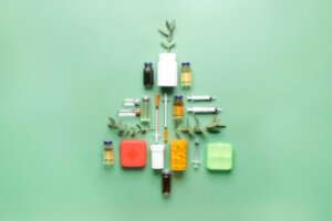 A Christmas tree comprised of vials, bottles, and medicine sits against a green background.