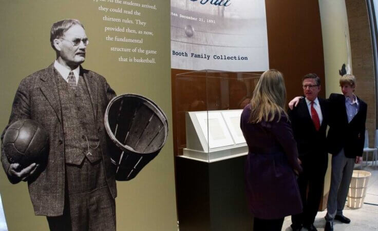 David, center, and Chandler Booth look at Suzanne Deal Booth as they pose for a photo next to James Naismith's original rules of Basket Ball on display at the Nelson-Atkins Museum of Art on Friday, March 4, 2011, in Kansas City, Mo. (AP Photo/Ed Zurga)