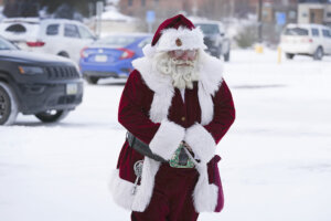 Santa Dale, no last name given, walks through the snow covered parking lot as he arrives at Merle Hay Mall, Friday, Dec. 23, 2022, in Des Moines, Iowa. (AP Photo/Charlie Neibergall)