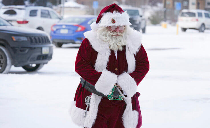 Santa Dale, no last name given, walks through the snow covered parking lot as he arrives at Merle Hay Mall, Friday, Dec. 23, 2022, in Des Moines, Iowa. (AP Photo/Charlie Neibergall)