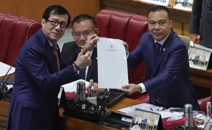 Indonesian Law and Human Right Minister Yasonna Laoly, left, pose for the media with Deputy House Speaker Sufmi Dasco Ahmad, center, during a session ratifying the country's new criminal code at the parliament building in Jakarta, Indonesia, Tuesday, Dec. 6, 2022. Indonesia's Parliament passed a long-awaited and controversial revision of its penal code Tuesday that criminalizes extramarital sex for citizens and visiting foreigners alike. (AP Photo)