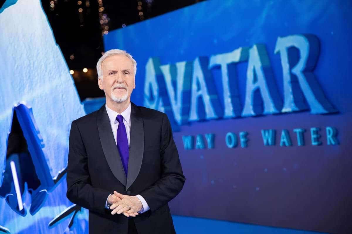 James Cameron stands in front of an Avatar: The way of water banner