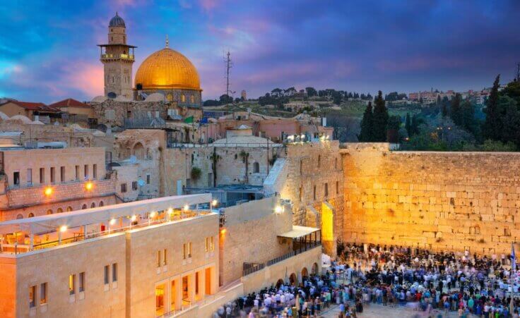 People gather near the Western Wall in Jerusalem at sunset with the Dome of the Rock in the background. © By rudi1976/stock.adobe.com