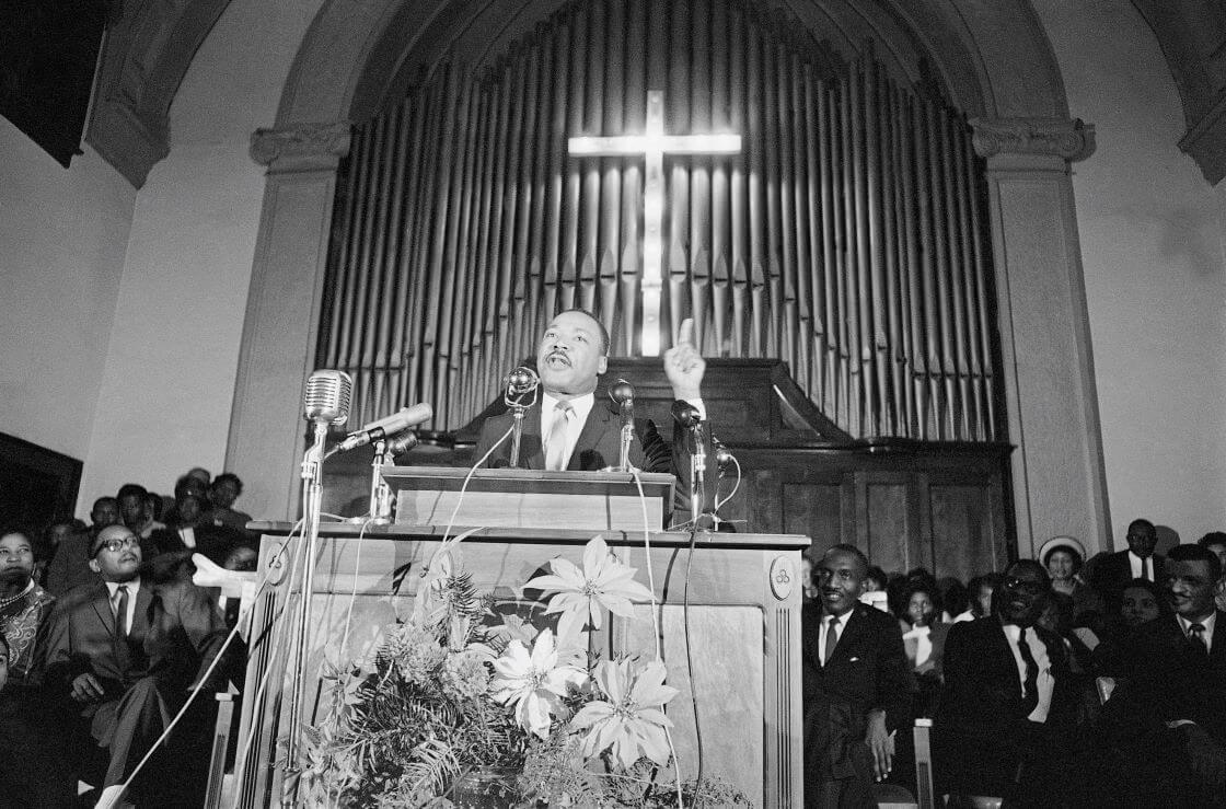 Dr. Martin Luther King Jr., center, speaks to a wildly cheering crowd of African American supporters, Jan. 2, 1965, Selma, Ala. King was calling for a new African American voter registration drive throughout Alabama and promising to "march on the ballot boxes" unless African American are given the right to vote. (AP Photo/Horace Cort)