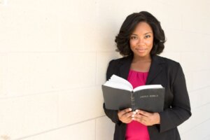 A woman holds a Bible open while looking straight ahead. © By pixelheadphoto/stock.adobe.com