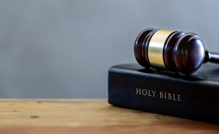 A gavel rests on top of a closed Bible. © By doidam10/stock.adobe.com