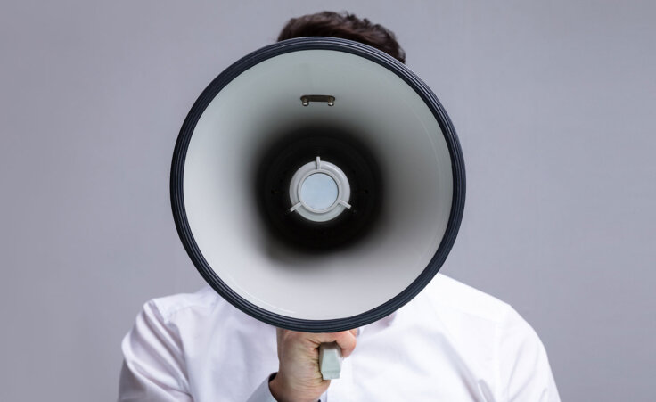 A man in white shirt holds a megaphone toward the camera. © By Andrey Popov/stock.adobe.com. In the West, Christian persecution can often look like attacks on your belief or character.