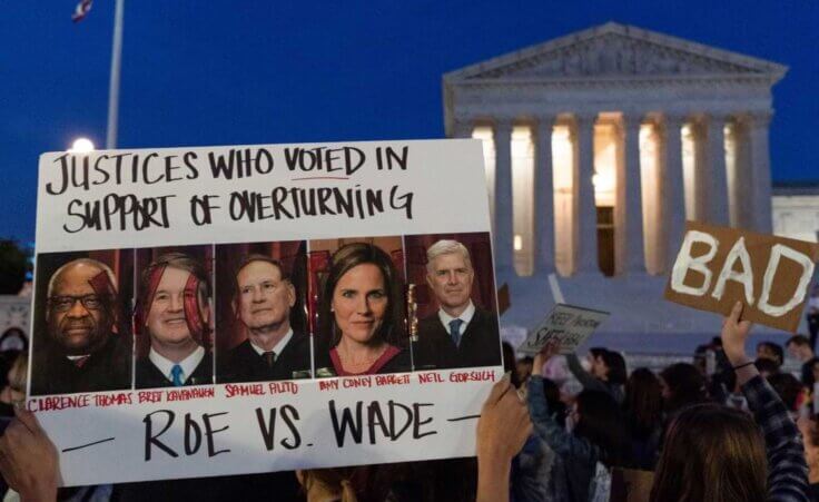 FILE - Nikki Tran holds up a sign with pictures of U.S. Supreme Court Justices, from left, Clarence Thomas, Brett Kavanaugh, Samuel Alito, Amy Coney Barrett and Neil Gorsuch, as demonstrators protest outside of the Supreme Court, May 3, 2022, in Washington. On Tuesday, Jan. 10, 2023. (AP Photo/Jacquelyn Martin, File) The Satanic Temple is now launching an abortion clinic named after Samuel Alito's mom due to his writing of the majority opinion that overturned Roe v. Wade.