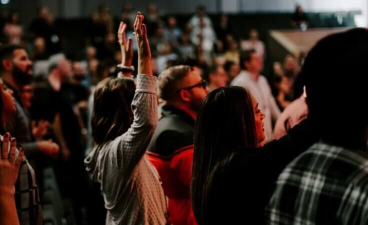 Stock photo: A woman raises her hands in the air during a worship service, a scene similar to that at the Asbury revival, which has now spread to 20 college campuses. © By tutye/stock.adobe.com