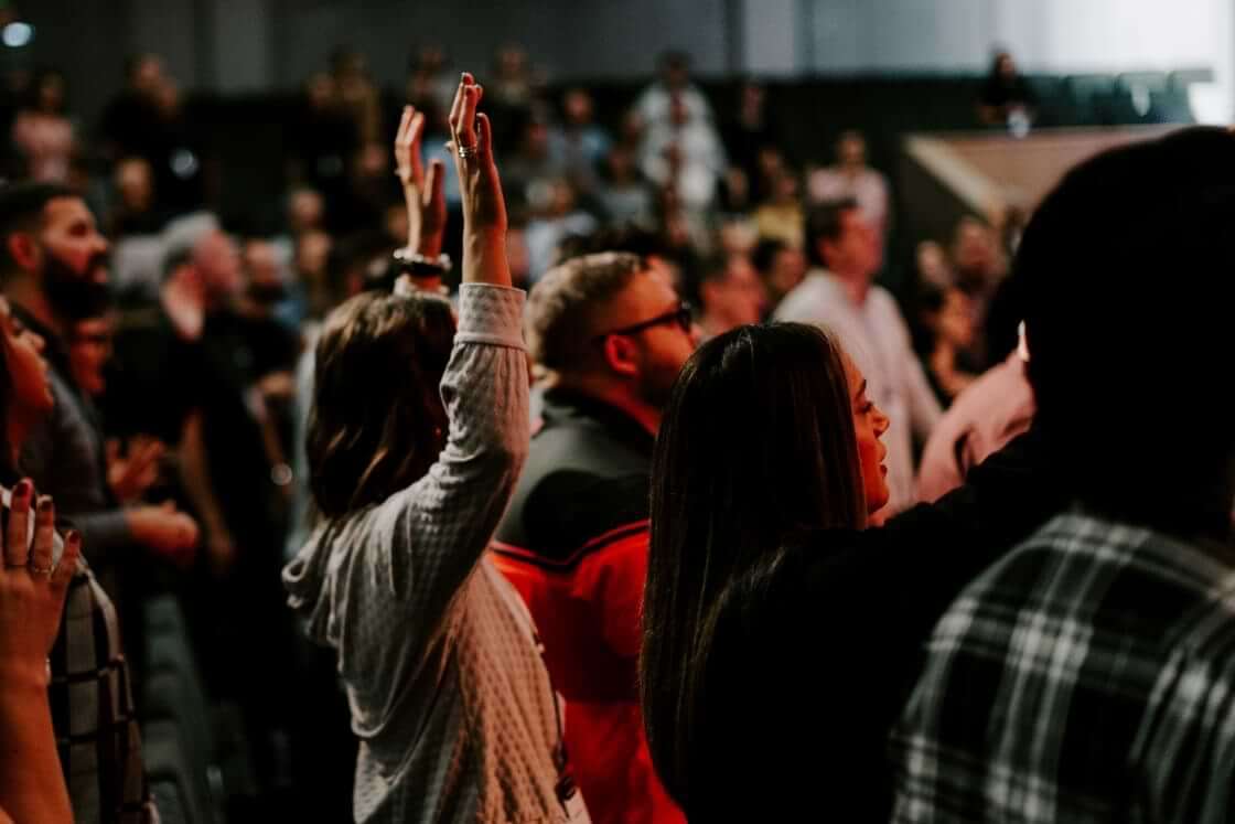 Stock photo: A woman raises her hands in the air during a worship service, a scene similar to that at the Asbury revival, which has now spread to 20 college campuses. © By tutye/stock.adobe.com