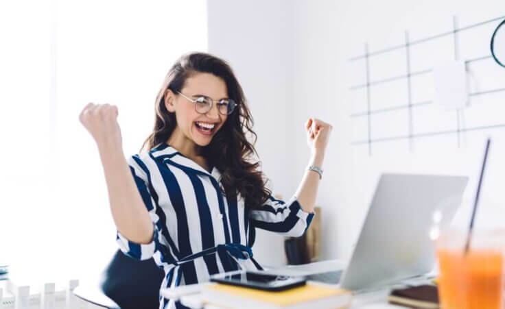Stock photo: A young woman celebrates, arms and fists in the air, in front of an open laptop. © By BullRun/stock.adobe.com. Canadian lottery winner Juliette Lamour is the youngest winner of Canada's lottery, winning $48 million on her 18th birthday.