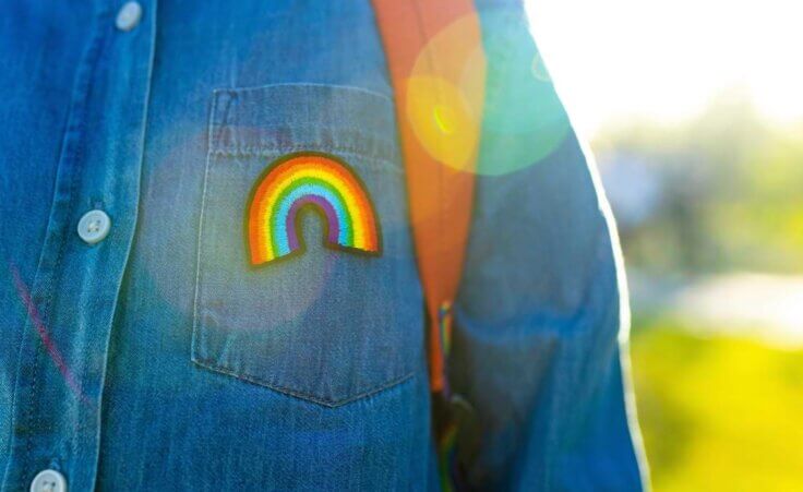 Child with backpack and rainbow button. Schools in Austin set to celebrate pride week