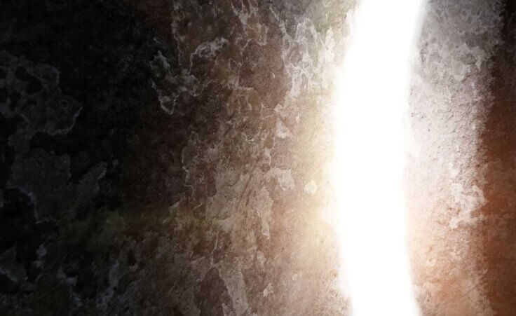 A close-up of a large stone rolling away from a tomb with a bright light shining from within. © By Balazs/stock.adobe.com | Did the resurrection of Jesus really happen?