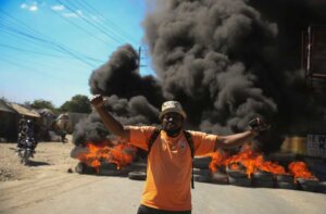 A protester shouts anti-government slogans by a burning barricade set up by members of the police to protest bad police governance in Port-au-Prince, Haiti, Thursday, Jan. 26, 2023. A wave of grisly killings of police officers by gangs has spurred outrage and protests by Haitians. (AP Photo/Odelyn Joseph)