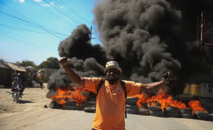 A protester shouts anti-government slogans by a burning barricade set up by members of the police to protest bad police governance in Port-au-Prince, Haiti, Thursday, Jan. 26, 2023. A wave of grisly killings of police officers by gangs has spurred outrage and protests by Haitians. (AP Photo/Odelyn Joseph)