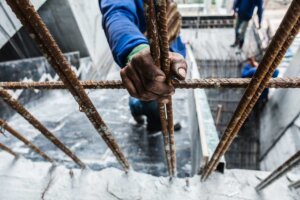 Unaccompanied minors enter US and work in harsh conditions, despite having sponsor families. A hand grips iron bars at a construction site.