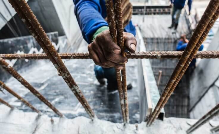 Unaccompanied minors enter US and work in harsh conditions, despite having sponsor families. A hand grips iron bars at a construction site.