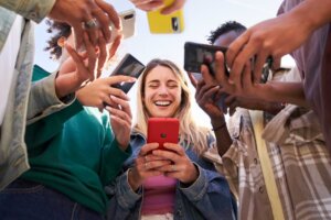A group of Gen Z young adults stands in a circle, all using smartphones. © By By CarlosBarquero/stock.adobe.com