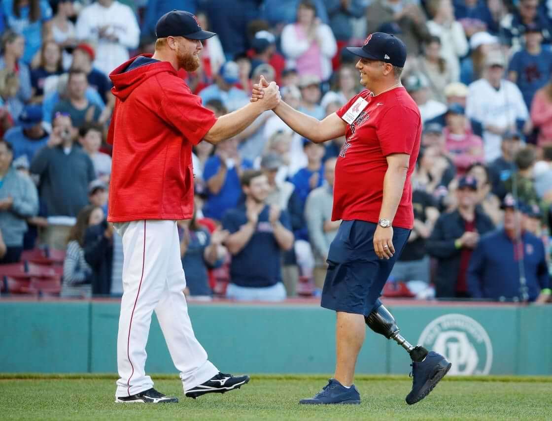 Boston Marathon bombing survivor J.P. Norden, right, of Stoneham, Mass., shakes hands with Boston Red Sox's Blaine Boyer after throwing out the ceremonial first pitch before a baseball game against the Kansas City Royals in Boston, Saturday, July 29, 2017. (AP Photo/Michael Dwyer)