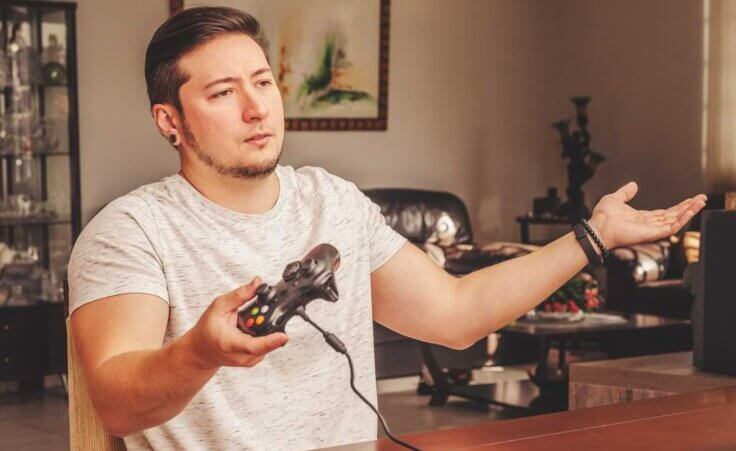 Man indignant and confused, holding a video game controller