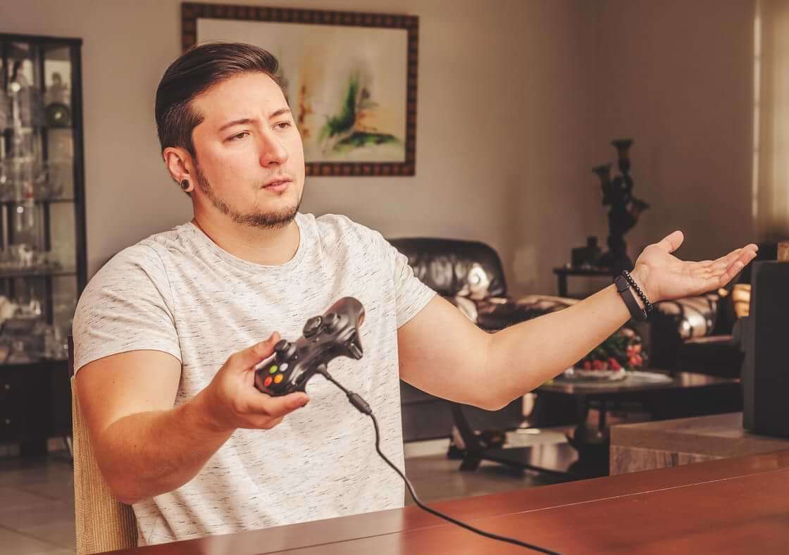 Man indignant and confused, holding a video game controller