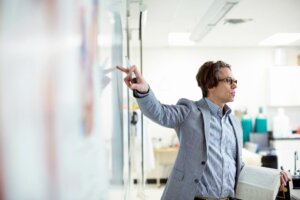 Professor teaching at class, pointing to a white board