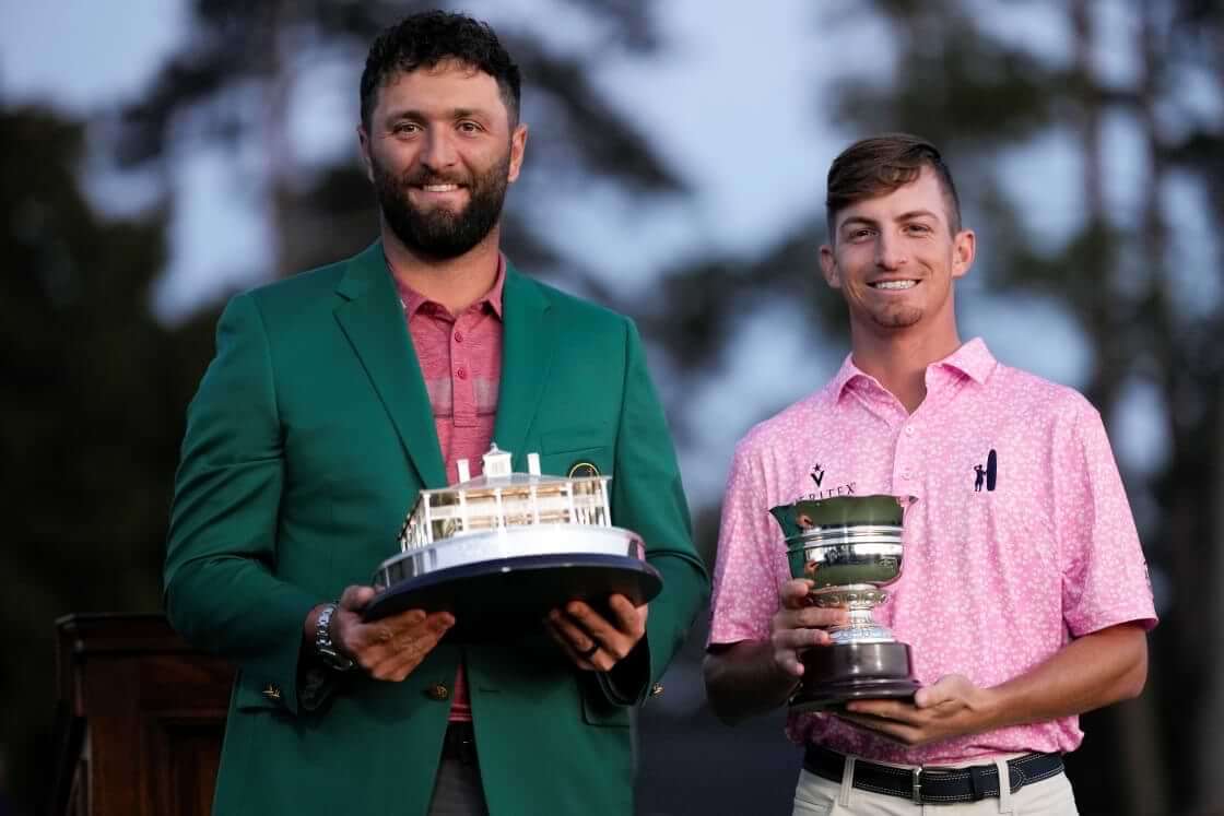 Jon Rahm, of Spain, holds up the Masters trophy as Sam Bennett holds the low amateur trophy after the Masters golf tournament at Augusta National Golf Club on Sunday, April 9, 2023, in Augusta, Ga. (AP Photo/David J. Phillip)