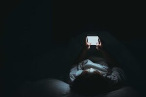 Woman using her phone at night, addicted to social media