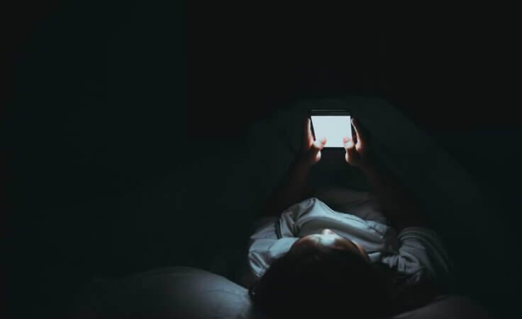 Woman using her phone at night, addicted to social media