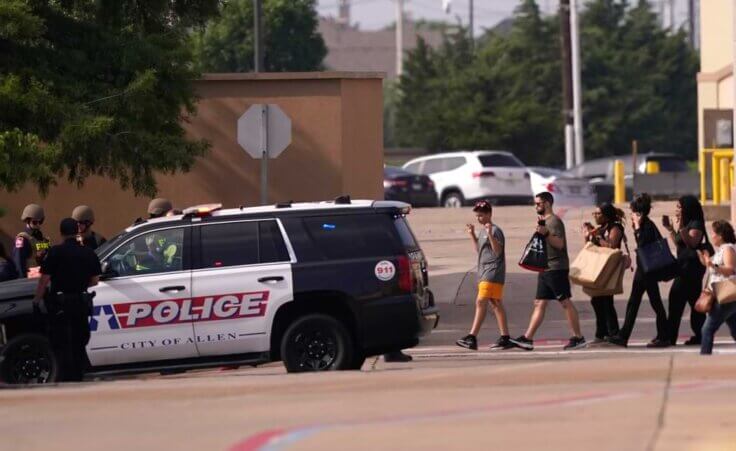 People raise their hands as they leave a shopping center following reports of a shooting, Saturday, May 6, 2023, in Allen, Texas.