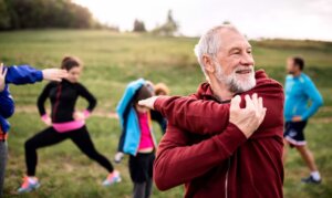 Large group of fit and active people doing exercise in nature, stretching