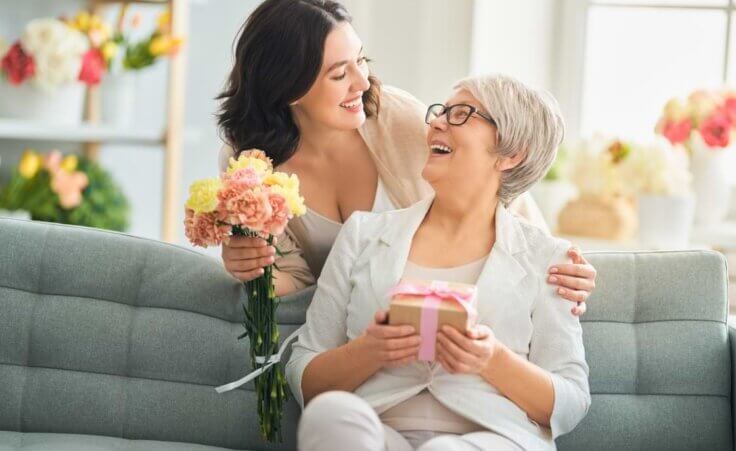 Young woman celebrating her mother on mother's day with flowers and gift