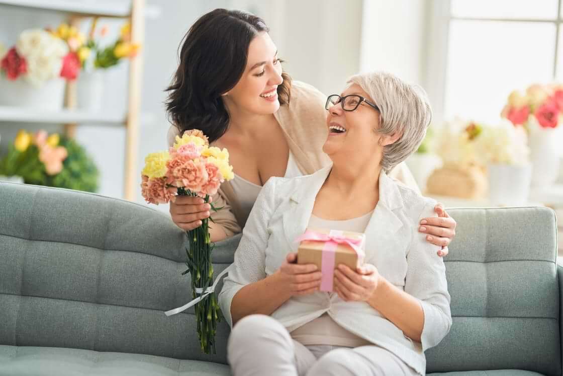 Young woman celebrating her mother on mother's day with flowers and gift