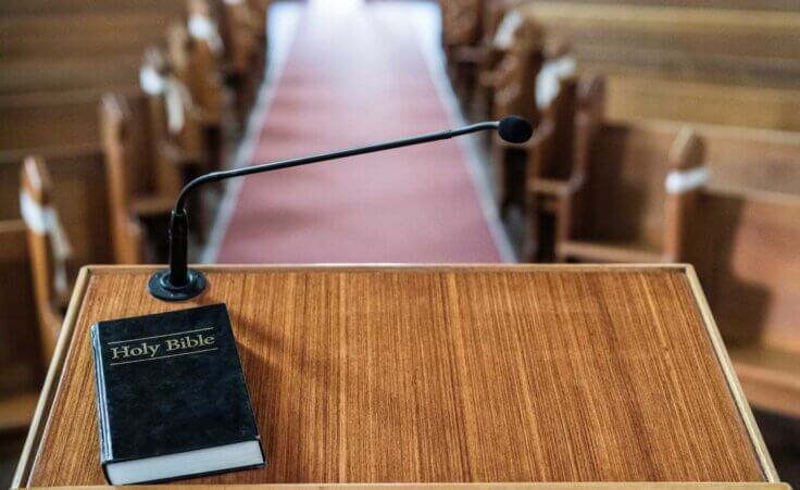 A closed Bible rests on a lectern in a pulpit of an empty church. © By Em Neems Photography/stock.adobe.com. A pastor job description should prioritize preaching and teaching God's word.