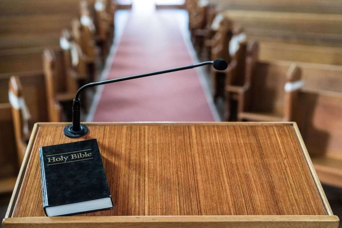 A closed Bible rests on a lectern in a pulpit of an empty church. © By Em Neems Photography/stock.adobe.com. A pastor job description should prioritize preaching and teaching God's word.