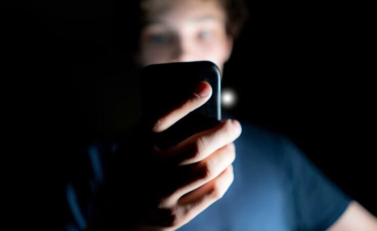 Teen looking at phone in a dark room