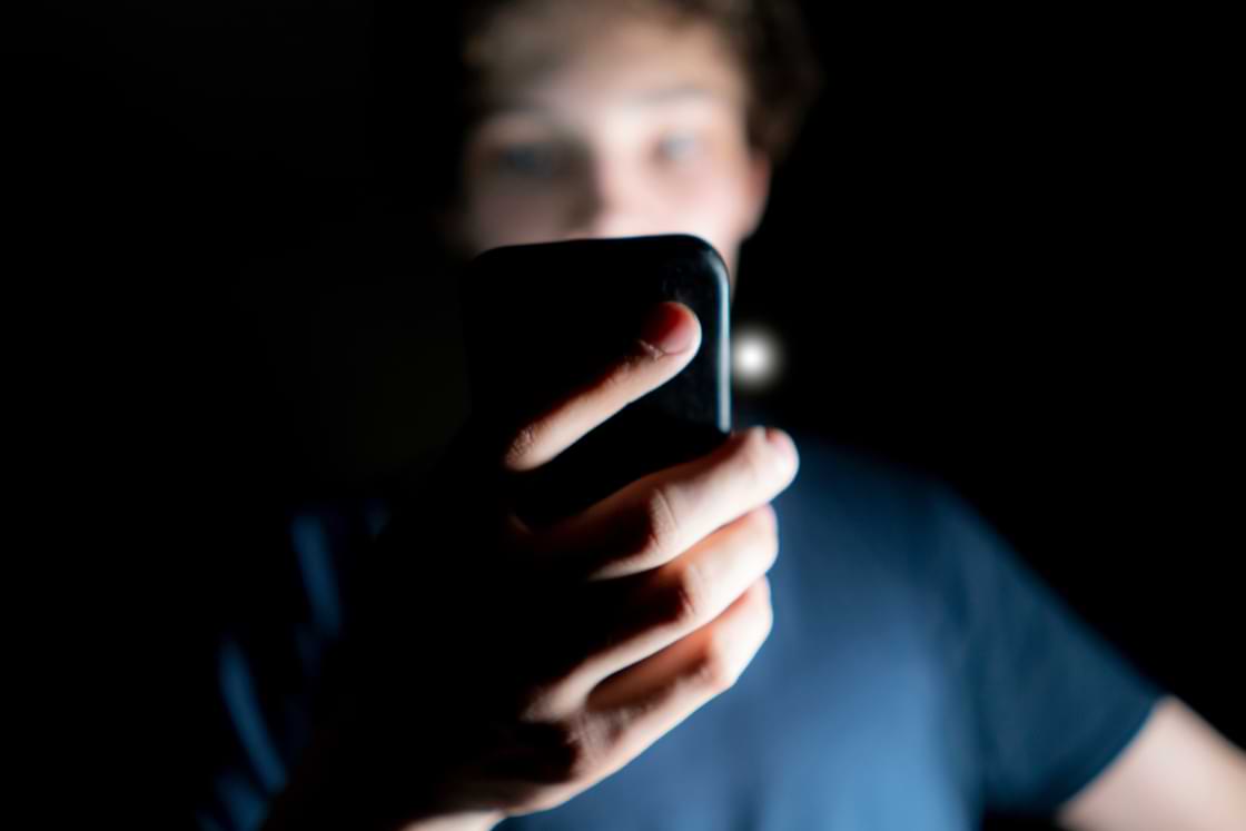 Teen looking at phone in a dark room
