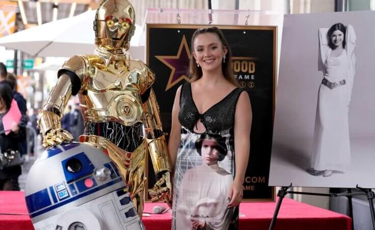 Billie Lourd, daughter of the late actress Carrie Fisher, pictured at right and on Lourd's dress, poses alongside "Star Wars" characters C-3PO and R2-D2 at a posthumous ceremony honoring Fisher with a star on the Hollywood Walk of Fame in Los Angeles on Thursday, May 4, 2023. (AP Photo/Chris Pizzello). The original Princess Leia dress pictured here failed to bring in an expected $2 million at a recent auction.