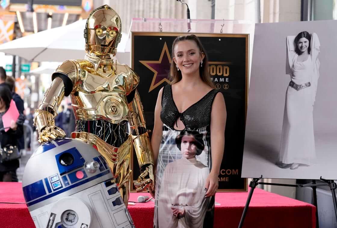 Billie Lourd, daughter of the late actress Carrie Fisher, pictured at right and on Lourd's dress, poses alongside "Star Wars" characters C-3PO and R2-D2 at a posthumous ceremony honoring Fisher with a star on the Hollywood Walk of Fame in Los Angeles on Thursday, May 4, 2023. (AP Photo/Chris Pizzello). The original Princess Leia dress pictured here failed to bring in an expected $2 million at a recent auction.