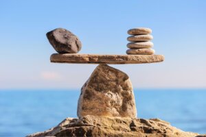 Rocks comprise a balanced scale, with a single large gray rock on left side balanced by four slim white rocks on the right—an illustration of living with both grace and truth. © By styf/stock.adobe.com