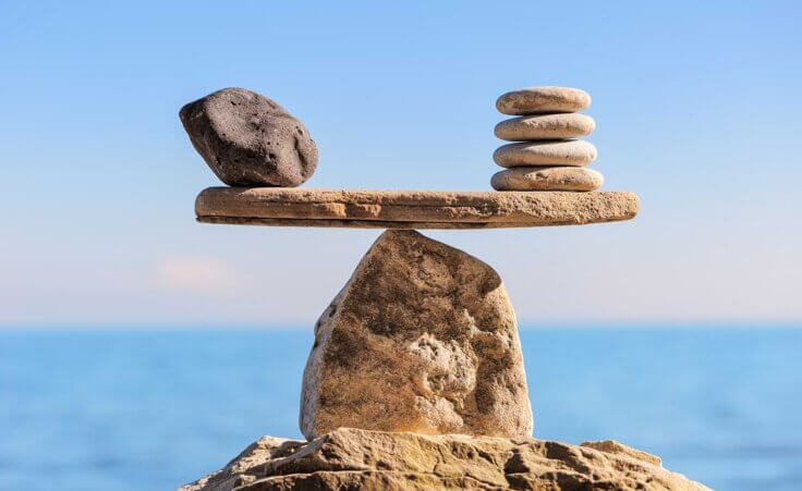 Rocks comprise a balanced scale, with a single large gray rock on left side balanced by four slim white rocks on the right—an illustration of living with both grace and truth. © By styf/stock.adobe.com