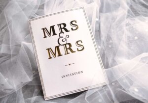 A white wedding invitation with black lettering says Mrs & Mrs Invitation. © By johannknox/stock.adobe.com