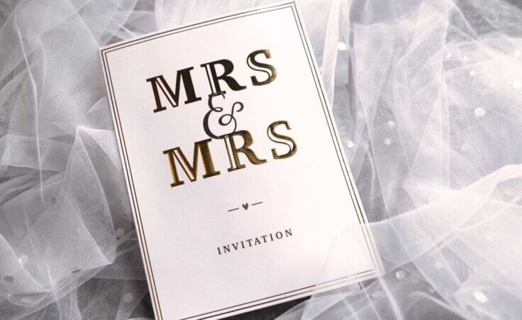 A white wedding invitation with black lettering says Mrs & Mrs Invitation. © By johannknox/stock.adobe.com