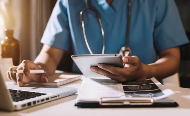 Medical student working on laptop in scrubs