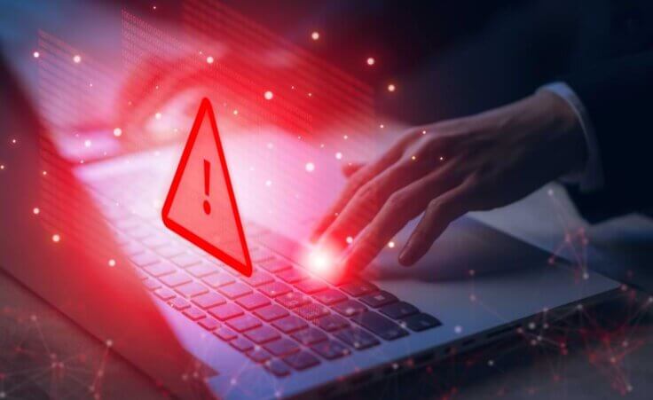 A hand presses a keyboard key on an open laptop with a red warning sign superimposed on the image © By Pungu x/stock.adobe.com. China has reportedly hidden malware deep inside networks controlling key infrastructure connected to US military bases.