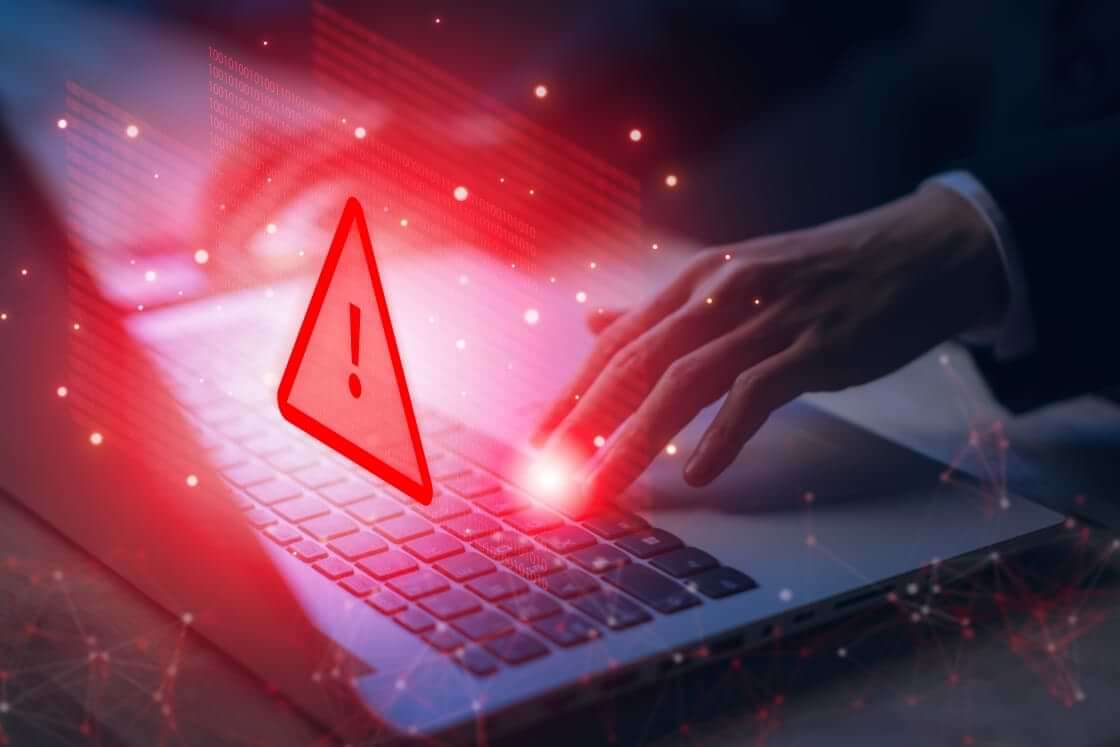 A hand presses a keyboard key on an open laptop with a red warning sign superimposed on the image © By Pungu x/stock.adobe.com. China has reportedly hidden malware deep inside networks controlling key infrastructure connected to US military bases.