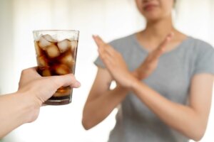 A woman crosses her hands in an X as someone offers her a diet soda. The WHO recently declared that the artificial sweetener Aspartame may cause cancer, resulting in diet drink sales plummeting. © By KomootP/stock.adobe.com