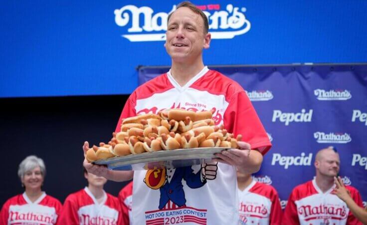 Competitive eater Joey Chestnut holds a plate of hotdogs representing his world record for eating 76 hotdogs and buns in ten minutes during a weigh-in ceremony before the Nathan's Famous July Fourth hot dog eating contest, Monday, July 3, 2023, in New York. (AP Photo/John Minchillo)