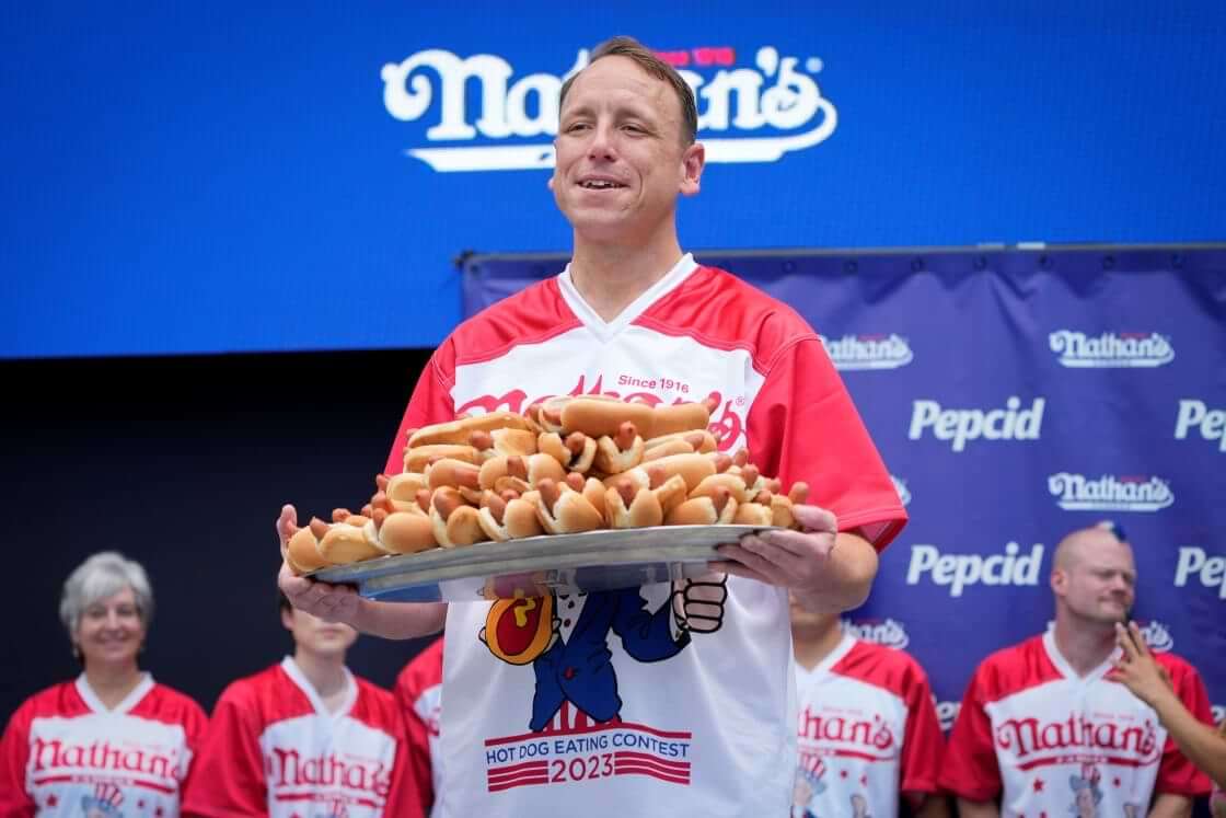 Competitive eater Joey Chestnut holds a plate of hotdogs representing his world record for eating 76 hotdogs and buns in ten minutes during a weigh-in ceremony before the Nathan's Famous July Fourth hot dog eating contest, Monday, July 3, 2023, in New York. (AP Photo/John Minchillo)