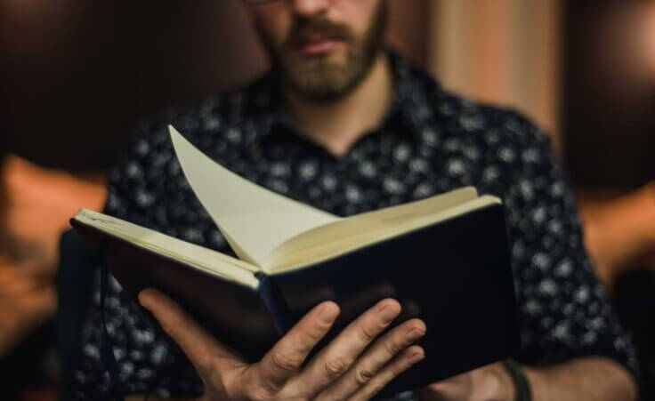 A man reads an open book in the palm of his hand. © By Lydia Goolia/stock.adobe.com